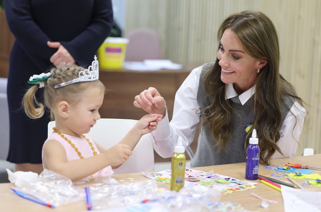 Kate Middleton smiles at a little girl wearing a tiara in Bracknell