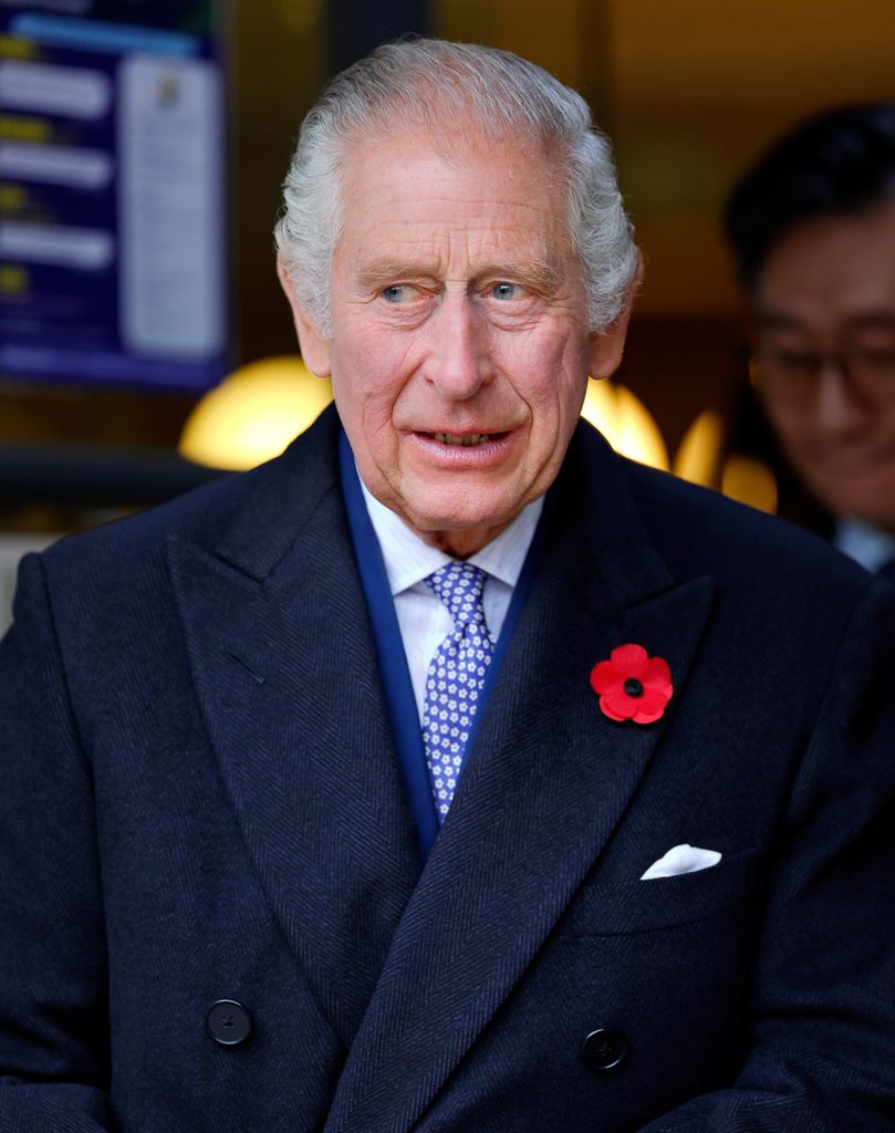 King Charles in navy coat with red poppy
