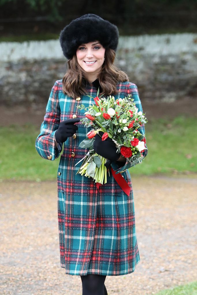 Kate Middleton wears a tartan coat and holds flowers attending Christmas Day 2017 services in Sandringham